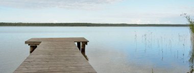 Orman nehri (göl) güneşli bir günde. Ahşap iskele. Clea gökyüzü, kristal berrak suda yansıyor. Idyllic manzara, kırsal manzara. Doğa, ekoloji, eko-turizm, yürüyüş, ekoloji beldesi, yerel turizm