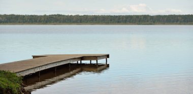 Orman nehri (göl) güneşli bir günde. Ahşap iskele. Clea gökyüzü, kristal berrak suda yansıyor. Idyllic manzara, kırsal manzara. Doğa, ekoloji, eko-turizm, yürüyüş, ekoloji beldesi, yerel turizm