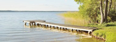 Orman nehri (göl) güneşli bir günde. Ahşap iskele. Clea gökyüzü, kristal berrak suda yansıyor. Idyllic manzara, kırsal manzara. Doğa, ekoloji, eko-turizm, yürüyüş, ekoloji beldesi, yerel turizm