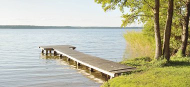 Orman nehri (göl) güneşli bir günde. Ahşap iskele. Clea gökyüzü, kristal berrak suda yansıyor. Idyllic manzara, kırsal manzara. Doğa, ekoloji, eko-turizm, yürüyüş, ekoloji beldesi, yerel turizm