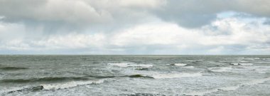 Fırtınadan sonra dramatik günbatımı bulutları altında Baltık Denizi. Dalgalar, su sıçratma. Destansı deniz manzarası. Kasırga, fırtına, sert hava, meteoroloji, ekoloji, iklim değişikliği, doğal olaylar