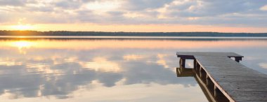 Orman Gölü (nehir) gün batımında. Ahşap iskele. Parlayan bulutlar, durgun ve berrak suda simetri yansımaları. Idyllic manzara. Doğa, ekoloji, ekolojik rezerv, eko-turizm, yürüyüş, tatiller