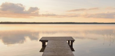 Orman Gölü (nehir) gün batımında. Ahşap iskele. Parlayan bulutlar, durgun ve berrak suda simetri yansımaları. Idyllic manzara. Doğa, ekoloji, ekolojik rezerv, eko-turizm, yürüyüş, tatiller