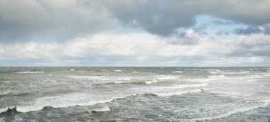 Fırtınadan sonra dramatik günbatımı bulutları altında Baltık Denizi. Dalgalar, su sıçratma. Destansı deniz manzarası. Kasırga, fırtına, sert hava, meteoroloji, ekoloji, iklim değişikliği, doğal olaylar