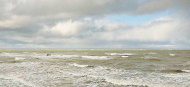 Fırtınadan sonra dramatik günbatımı bulutları altında Baltık Denizi. Dalgalar, su sıçratma. Destansı deniz manzarası. Kasırga, fırtına, sert hava, meteoroloji, ekoloji, iklim değişikliği, doğal olaylar