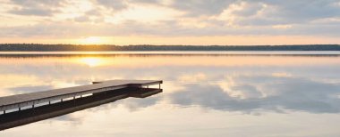 Orman Gölü (nehir) gün batımında. Ahşap iskele. Parlayan bulutlar, durgun ve berrak suda simetri yansımaları. Idyllic manzara. Doğa, ekoloji, ekolojik rezerv, eko-turizm, yürüyüş, tatiller
