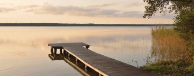 Orman Gölü (nehir) gün batımında. Ahşap iskele. Parlayan bulutlar, durgun ve berrak suda simetri yansımaları. Idyllic manzara. Doğa, ekoloji, ekolojik rezerv, eko-turizm, yürüyüş, tatiller
