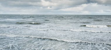 Fırtınadan sonra dramatik günbatımı bulutları altında Baltık Denizi. Dalgalar, su sıçratma. Destansı deniz manzarası. Kasırga, fırtına, sert hava, meteoroloji, ekoloji, iklim değişikliği, doğal olaylar