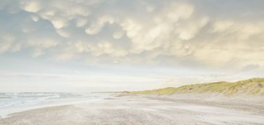 Gün batımında Baltık kıyısı. Açık günbatımı gökyüzü, parlayan bulutlar. Idyllic manzara. Doğa, tatiller, eğlence. Çevre turizmi. Panoramik görünüm