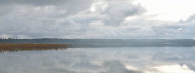 Gün batımında Orman Nehri (Lake). Dramatik gökyüzü, karanlık, parlak bulutlar. Kristal berrak suda simetri yansımaları. Panoramik sonbahar manzarası. Doğa, çevre, ekoloji, hava durumu, iklim değişikliği