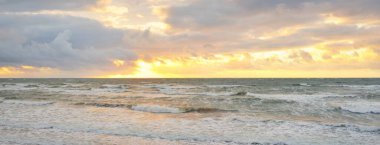 Gün batımında Baltık kıyılarından panoramik manzara. Dramatik bulutlar, parlayan bulutlar, fırtınadan sonra altın güneş ışığı. Doğa, çevre, iklim değişikliği, kararsız hava