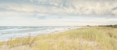 Baltık kıyıları (kum tepeleri) fırtınadan sonra gün batımında. Açık gökyüzü, parlayan bulutlar, rüzgar. Sonbahar manzarası. Doğa, çevre koruma, ekoloji, eko-turizm, yerel seyahat