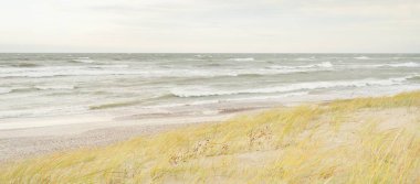 Baltık kıyıları (kum tepeleri) fırtınadan sonra gün batımında. Açık gökyüzü, parlayan bulutlar, rüzgar. Sonbahar manzarası. Doğa, çevre koruma, ekoloji, eko-turizm, yerel seyahat