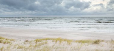 Gün batımında Baltık kıyısı. Açık günbatımı gökyüzü, parlayan bulutlar. Idyllic manzara. Doğa, tatiller, eğlence. Çevre turizmi. Panoramik görünüm