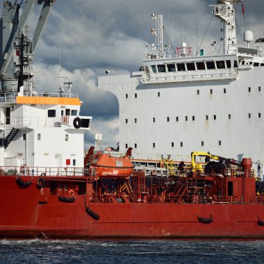 Kargo gemileri iskele terminaline yükleniyor. Vinçler arka planda. Baltık Denizi. Bunkering, akaryakıt ve enerji üretimi, arz, teknoloji, lojistik, hizmet, sanayi, ticaret