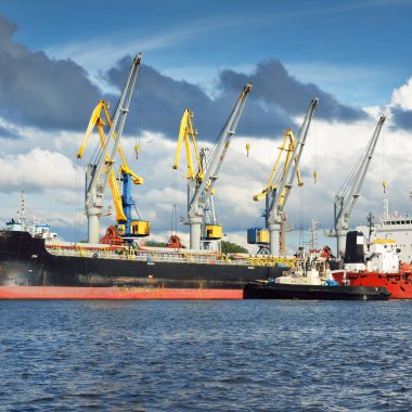 Kargo gemileri iskele terminaline yükleniyor. Vinçler arka planda. Baltık Denizi. Bunkering, akaryakıt ve enerji üretimi, arz, teknoloji, lojistik, hizmet, sanayi, ticaret