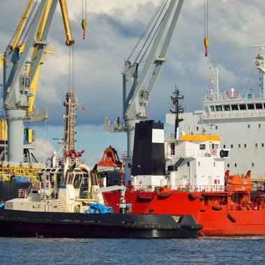 Kargo gemileri iskele terminaline yükleniyor. Vinçler arka planda. Baltık Denizi. Bunkering, akaryakıt ve enerji üretimi, arz, teknoloji, lojistik, hizmet, sanayi, ticaret