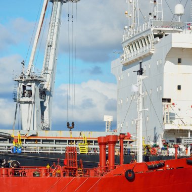 Kargo gemileri iskele terminaline yükleniyor. Vinçler arka planda. Baltık Denizi. Bunkering, akaryakıt ve enerji üretimi, arz, teknoloji, lojistik, hizmet, sanayi, ticaret