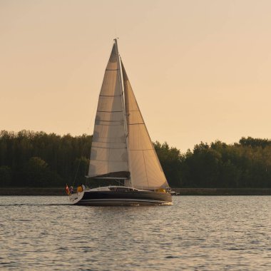 Günbatımında Baltık Denizi 'nde yelkenli yelkenli yelkenli. Fırtınadan sonra gökyüzü açık, altın güneş ışığı. Ulaşım, seyahat, gezi, spor, eğlence, boş zaman aktivitesi, yarış, yelkenli yarışı