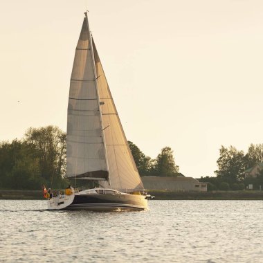 Günbatımında Baltık Denizi 'nde yelkenli yelkenli yelkenli. Fırtınadan sonra gökyüzü açık, altın güneş ışığı. Ulaşım, seyahat, gezi, spor, eğlence, boş zaman aktivitesi, yarış, yelkenli yarışı