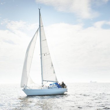 Açık denizde yelkenli yelkenli yelkenli. Gökyüzü açık, bulutlu. Yelkenlinin manzarası. Ulaşım, seyahat, spor, eğlence, boş zaman aktivitesi, yarış, yelkenli yarışı. Panorama, boşluğu kopyala