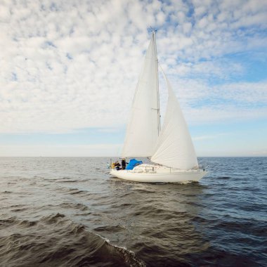 Açık denizde yelkenli yelkenli yelkenli. Gökyüzü açık, bulutlu. Yelkenlinin manzarası. Ulaşım, seyahat, spor, eğlence, boş zaman aktivitesi, yarış, yelkenli yarışı. Panorama, boşluğu kopyala