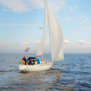 Açık denizde yelkenli yelkenli yelkenli. Gökyüzü açık, bulutlu. Yelkenlinin manzarası. Ulaşım, seyahat, spor, eğlence, boş zaman aktivitesi, yarış, yelkenli yarışı. Panorama, boşluğu kopyala