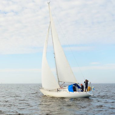 Açık denizde yelkenli yelkenli yelkenli. Gökyüzü açık, bulutlu. Yelkenlinin manzarası. Ulaşım, seyahat, spor, eğlence, boş zaman aktivitesi, yarış, yelkenli yarışı. Panorama, boşluğu kopyala