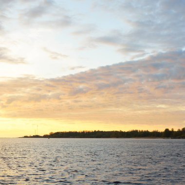 Fırtınadan sonra Baltık Denizi, yelkenli tekneden panoramik manzara. Orman kıyısı. Dramatik gün batımı gökyüzü. Parlayan bulutlar, altın güneş ışığı. Idyllic deniz manzarası. Doğa, gezi, seyahat yerleri