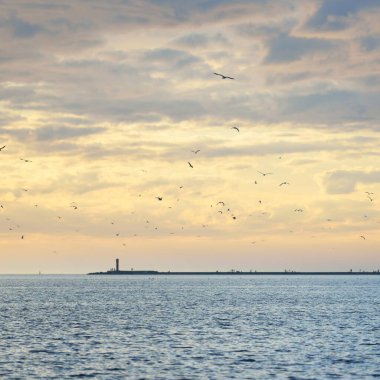 Fırtınadan sonra Baltık Denizi, yelkenli tekneden panoramik manzara. Deniz feneri, martılar. Dramatik gün batımı gökyüzü. Parlayan bulutlar, altın güneş ışığı. Idyllic deniz manzarası. Doğa, gezi, seyahat yerleri