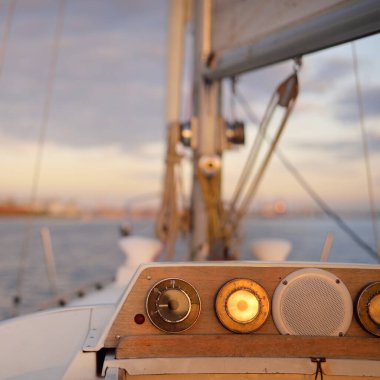 Beyaz yat gün batımında limana varacak. Güverteden pruva ve yelkenlere kadar yakın çekim. Fırtınadan sonra dramatik bir gökyüzü. Baltık Denizi. Deniz aracı, ulaşım, hizmet, spor, eğlence kavramları