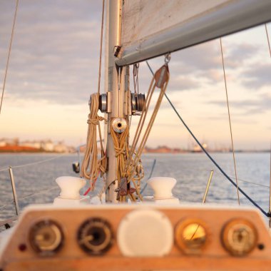 Beyaz yat gün batımında limana varacak. Güverteden pruva ve yelkenlere kadar yakın çekim. Fırtınadan sonra dramatik bir gökyüzü. Baltık Denizi. Deniz aracı, ulaşım, hizmet, spor, eğlence kavramları