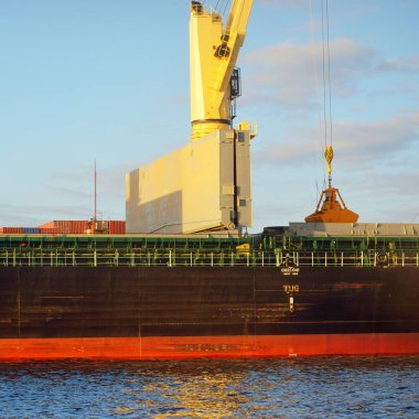 Liman terminalinde vinçleri yükleyen büyük bir yük gemisi (179 metre uzunluğunda). Baltık Denizi. Nakliye, lojistik, küresel iletişim, ekonomi, ticaret, sanayi, arz