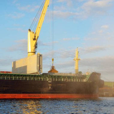 Liman terminalinde vinçleri yükleyen büyük bir yük gemisi (179 metre uzunluğunda). Baltık Denizi. Nakliye, lojistik, küresel iletişim, ekonomi, ticaret, sanayi, arz