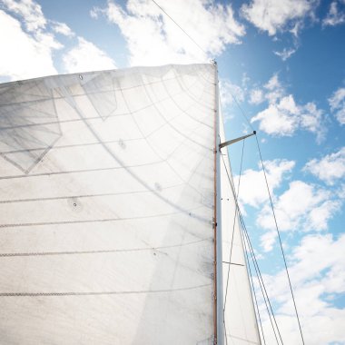 Açık bir günde açık denizde yelken açan beyaz yelkenli bir yat. Beyaz yelkenler mavi gökyüzüne karşı kümülüs bulutlarıyla yağmurdan önce. Ulaşım, seyahat, gezi, spor, eğlence, yarış, yelkenli yarışı