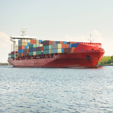 Konteyner gemisi (168 metre uzunluğunda) gün batımında limandan ayrılıyor. Baltık Denizi. Yük taşımacılığı, lojistik, küresel iletişim, dünya çapında taşımacılık, ekonomi, iş dünyası, sanayi