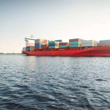 Konteyner gemisi (168 metre uzunluğunda) gün batımında limandan ayrılıyor. Baltık Denizi. Yük taşımacılığı, lojistik, küresel iletişim, dünya çapında taşımacılık, ekonomi, iş dünyası, sanayi