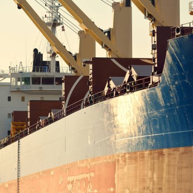 Büyük kargo gemisi (toplu taşıyıcı, 187 metre uzunluğunda) iskele terminalinde yükleme, arka planda vinçler. Yük taşımacılığı, lojistik, küresel iletişim, ekonomi, ticaret, sanayi