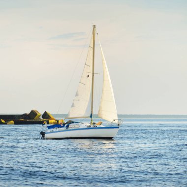 Günbatımında Baltık Denizi 'nde yelkenli yelkenli yelkenli. Fırtınadan sonra açık gökyüzü, yumuşak güneş ışığı. Deniz feneri. Ulaşım, seyahat, gezi, spor, eğlence, boş zaman aktivitesi, yarış, yelkenli yarışı