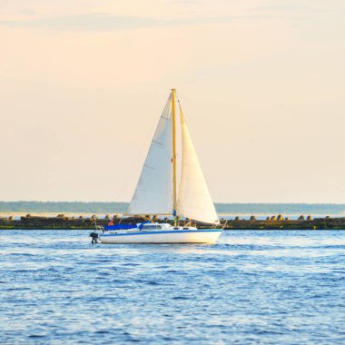 Günbatımında Baltık Denizi 'nde yelkenli yelkenli yelkenli. Fırtınadan sonra açık gökyüzü, yumuşak güneş ışığı. Deniz feneri. Ulaşım, seyahat, gezi, spor, eğlence, boş zaman aktivitesi, yarış, yelkenli yarışı