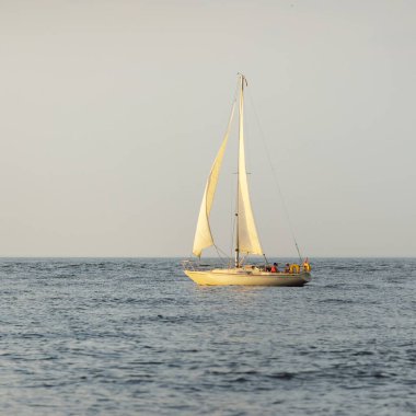 Baltık Denizi 'nde yelkenli bir yat. Gün batımı. Fırtınadan sonra dramatik bir gökyüzü, yumuşak güneş ışığı. Ulaşım, seyahat, seyahat, yat yarışı, spor, eğlence, eğlence, eğlence, yaşam tarzı, aile.