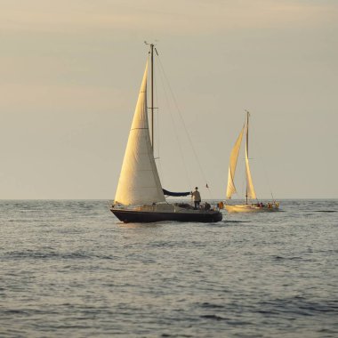 Baltık Denizi 'nde yelkenli bir yat. Gün batımı. Fırtınadan sonra dramatik bir gökyüzü, yumuşak güneş ışığı. Ulaşım, seyahat, seyahat, yat yarışı, spor, eğlence, eğlence, eğlence, yaşam tarzı, aile.