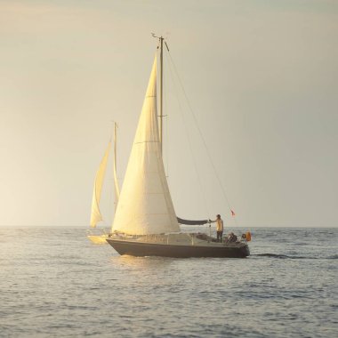 Baltık Denizi 'nde yelkenli bir yat. Gün batımı. Fırtınadan sonra dramatik bir gökyüzü, yumuşak güneş ışığı. Ulaşım, seyahat, seyahat, yat yarışı, spor, eğlence, eğlence, eğlence, yaşam tarzı, aile.