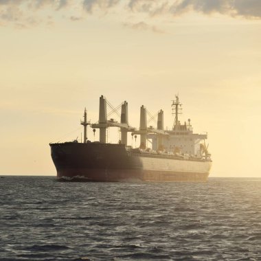 Büyük bir kargo gemisi (179.99 metre uzunluğunda) gün batımında Baltık Denizi 'nde yol alır. Nakliye, lojistik, küresel iletişim, ekonomi, sanayi, arz, çevre