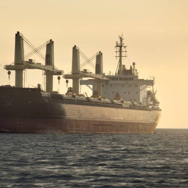 Büyük bir kargo gemisi (179.99 metre uzunluğunda) gün batımında Baltık Denizi 'nde yol alır. Nakliye, lojistik, küresel iletişim, ekonomi, sanayi, arz, çevre