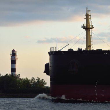 Büyük bir kargo gemisi (179.99 metre uzunluğunda) gün batımında Baltık Denizi 'nde yol alır. Nakliye, lojistik, küresel iletişim, ekonomi, sanayi, arz, çevre