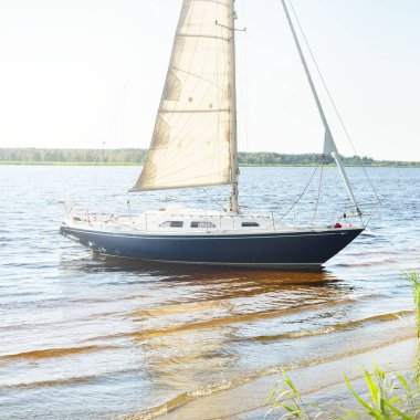 Kumlu kıyıya demirli mavi şalopeli yat (kumsalda otlarla kaplanmış). İsveç 'te, Avrupa' da. Doğa, yaz tatilleri, eğlence, gezi, spor, ulaşım. Hava görünümü