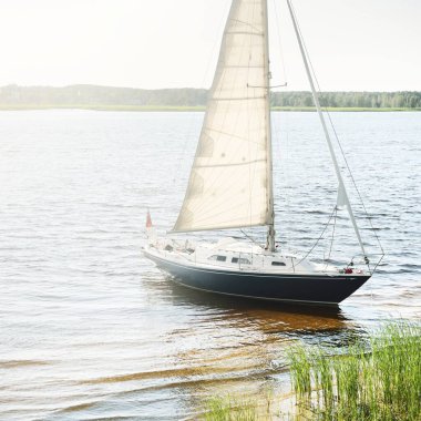 Kumlu kıyıya demirli mavi şalopeli yat (kumsalda otlarla kaplanmış). İsveç 'te, Avrupa' da. Doğa, yaz tatilleri, eğlence, gezi, spor, ulaşım. Hava görünümü