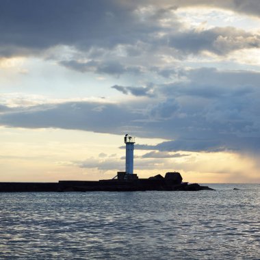 Güneş pilli deniz feneri. Baltık Denizi. Fırtınadan sonra dramatik günbatımı gökyüzü. Parlayan bulutlar, altın güneş ışığı. Umut ve barışın sembolü. Mimarlık, seyahat yerleri, navigasyon, yelkencilik.