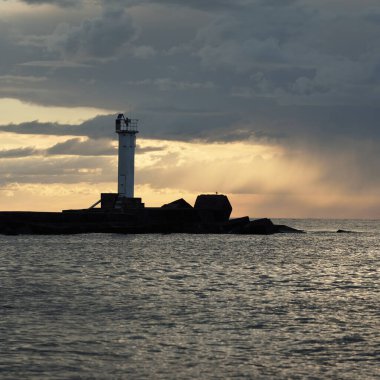 Güneş pilli deniz feneri. Baltık Denizi. Fırtınadan sonra dramatik günbatımı gökyüzü. Parlayan bulutlar, altın güneş ışığı. Umut ve barışın sembolü. Mimarlık, seyahat yerleri, navigasyon, yelkencilik.